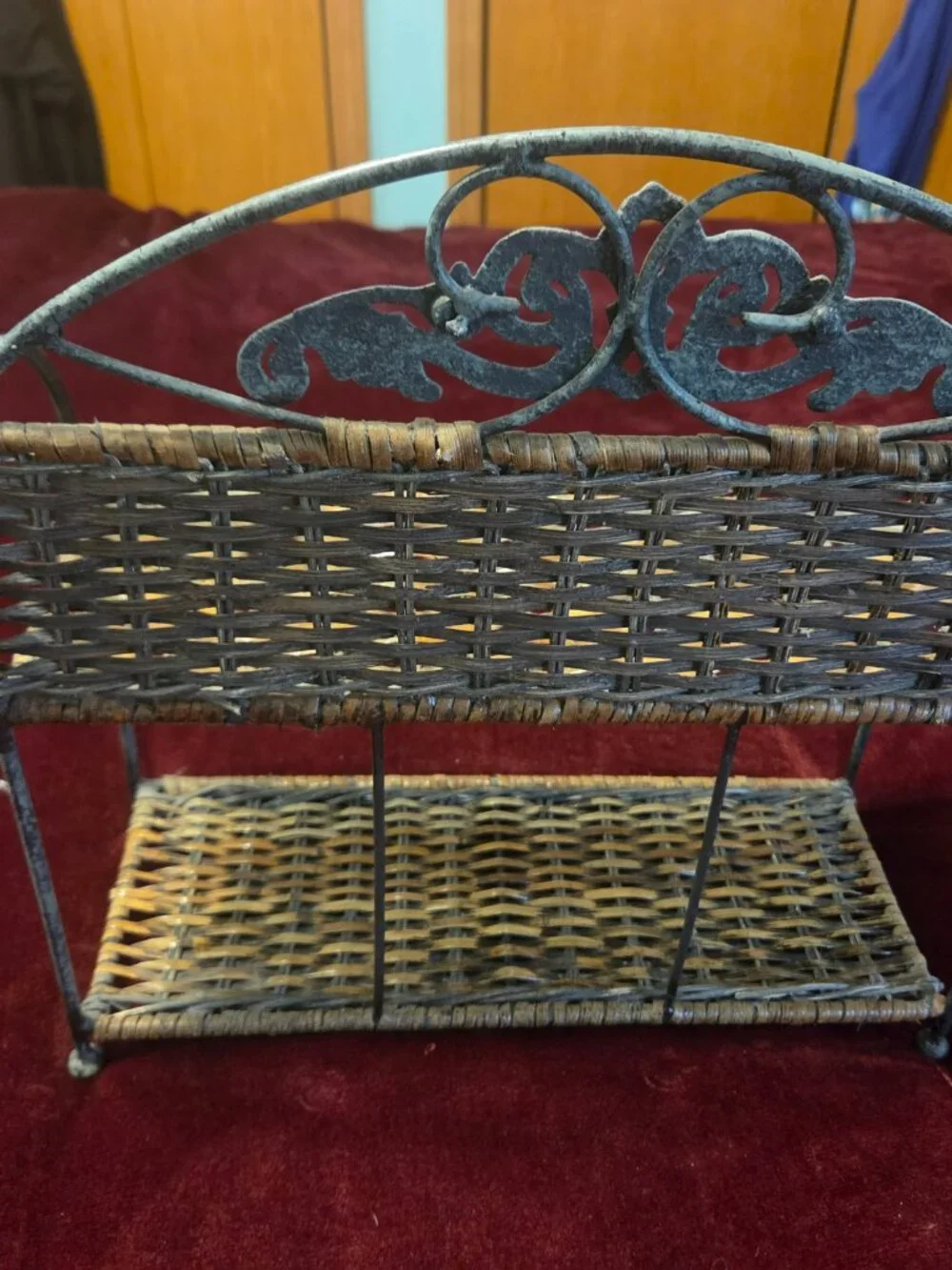 two tier wicker shelf with metal frame adorned with scrollwork some wear
